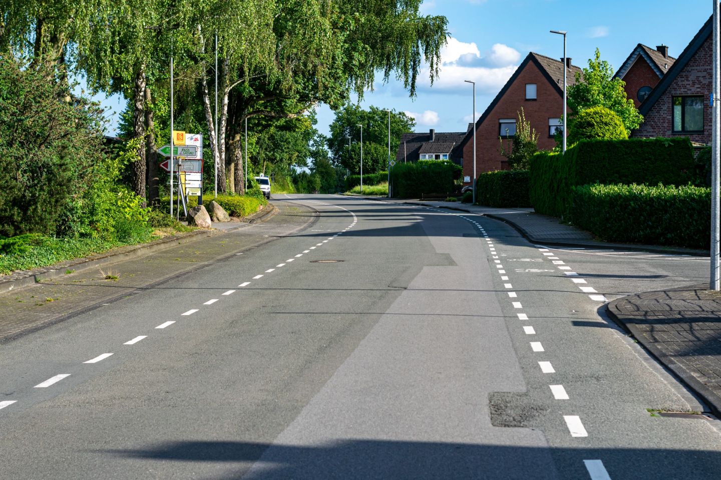Ruhige Wohnstraße mit Einfamilienhäusern und Vorgärten an einem Sommertag.